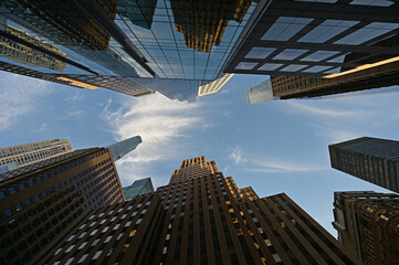 Naklejka premium Upward view of skyscrapers in New York City, New York against early morning sky with high altitude clouds.