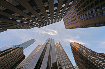 Fototapeta na wymiar Upward view of skyscrapers in New York City, New York against early morning sky with high altitude clouds.