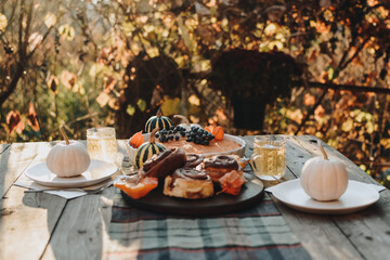 Thanksgiving festive table. Autumn style table setting with pumpkins, leaves and physalis. Pumpkin pie and cinnamon rolls. Cozy autumn scene. Flat lay. Fall styled composition.