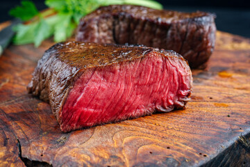 Traditional fried dry aged bison beef rump steak served as close-up in a rustic old wooden board