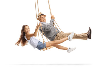 Cheerful grandfather and granddaughter swinging on wooden swings