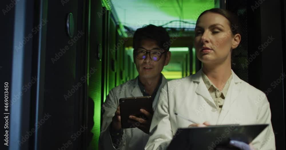 Poster diverse female and male it technicians in lab coats using tablet and laptop checking computer server