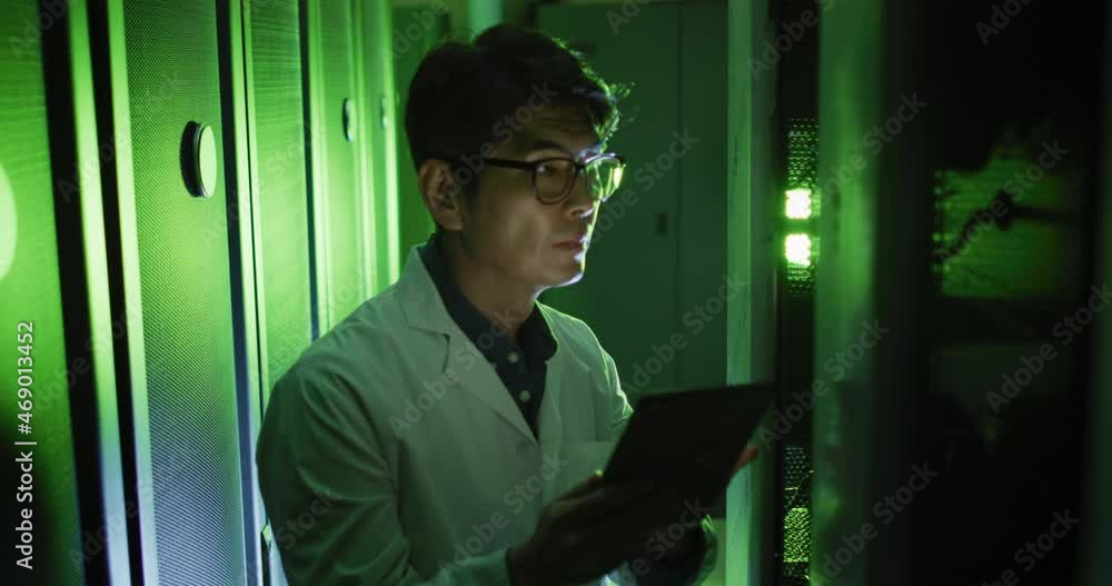 Poster asian male it technician in lab coat using tablet checking computer server