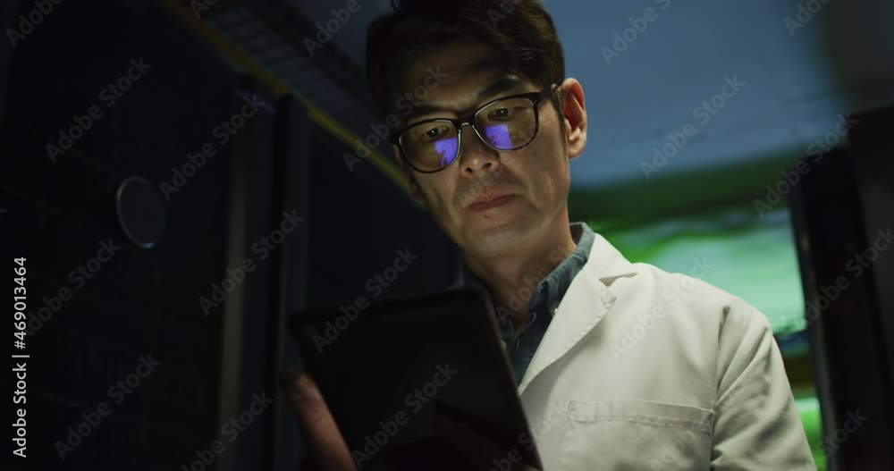 Poster asian male it technician in lab coat using tablet checking computer server