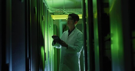 Asian male it technician in lab coat using tablet checking computer server