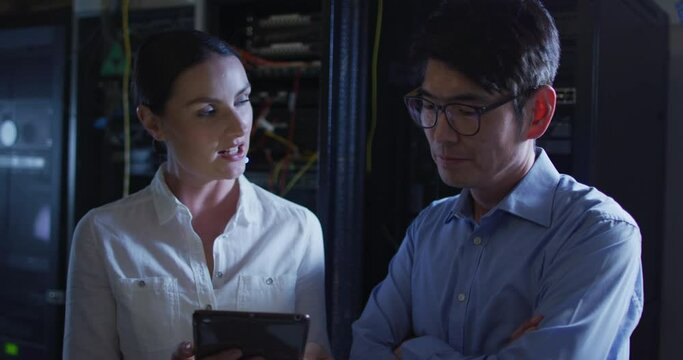 Diverse female and male it technicians using tablet checking computer server