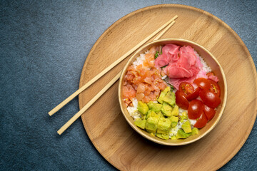 salmon poke bowl in wooden plate on dark background, copy space, close up