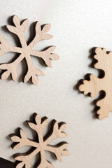 three wooden snowflakes on silver gray paper background