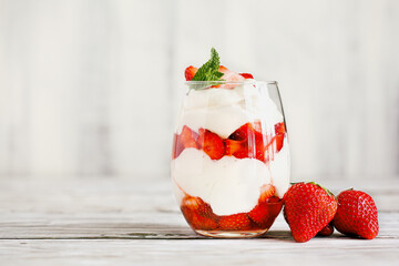 Healthy breakfast of strawberry parfait made with fresh fruit, and yogurt over a rustic white table. Selective focus with blurred background and foreground. - obrazy, fototapety, plakaty