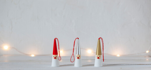 Three Santa Clauses on white background with garland lights