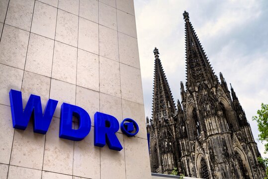 Cologne, Germany - May 23, 2021: logo on the facade of the WDR Broadcasting Building, in the background the Cologne Cathedral