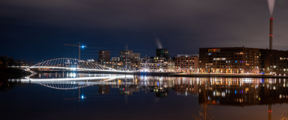 Beautiful city skyline casting reflections on the calm water during the night.