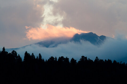 Clouds rolling over mountains at sunset