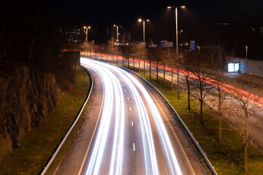 Traffic light trails of bypassing vehicles on the busy highway during nighttime.