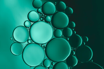 Pattern formed by a beautiful collection of bubbles created by  oil droplets on the surface of water and highlighted with metallic green lighting