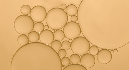 Oil droplets to  surface of water to produce a different sized bubbles which have been highlighted by the effects ofpale yellow  background
