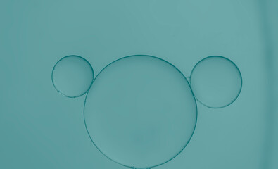Oil droplets on water surface with blue-green light effects background.