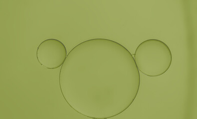 Abstract oil droplets on water surface creating bubble and circle shape with green light effects background.
