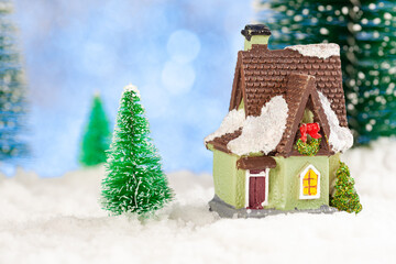 Christmas greeting card. Small toy house in the snow. Artificial spruce