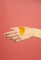 honey flowing on female hand isolated on pink background
