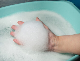 Foam in hand. Washing dishes. Washing basin.