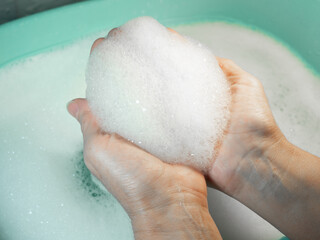 Foam in hand. Washing dishes. Washing basin.
