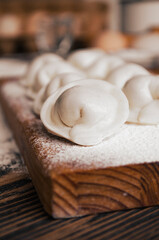 Raw homemade dumplings on a wooden board. Molding dumplings..