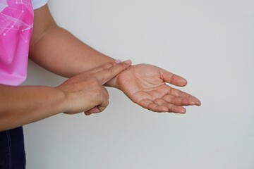 Concept : Medical, health care. Pulse measurement. Self taking care at home. Woman uses two fingers to touch her wrist to check pulse.