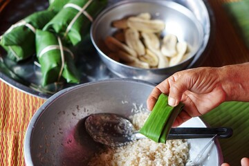 Rice and banana on leaf. The method of making khao tom mat in Thai or Sticky rice cakes bundle wrapped banana leaves , local food. Thailand. Concept: cooking method. Thai traditional  lifestyle.