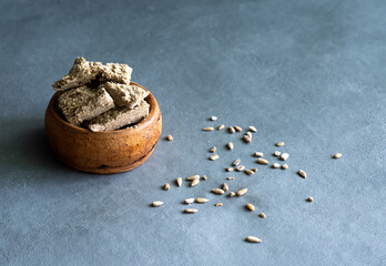 Sunflower halva in a clay plate on a gray background. Made from sunflower seeds. High quality photo