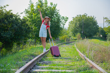 the traveler walks on the railroad with a suitcase