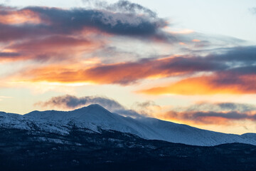 Storm brewing clouds above snow capped mountains in northern Canada with lake and wilderness area. Stunning landscape, background, desktop picture. 