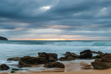 Fototapeta na wymiar Low cloud covered sunrise seascape with rocks