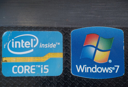 Intel and Windows 7 logo on an old laptop. Technological evolution - concept. USA, New York. November, 13, 2021