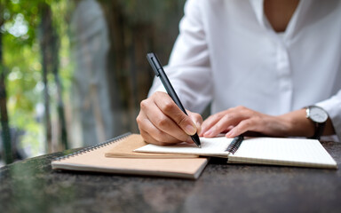 Closeup image of a woman writing on a notebook on the table