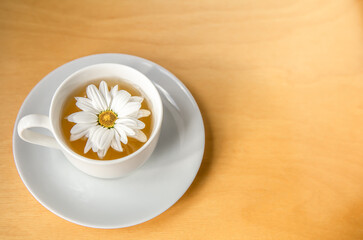 Cup of tea with chamomile flower on a wooden background, copy space.