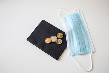 Close-up of passport, mask and coins on a white background.