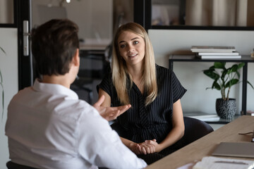 Professional young male hr manager holding job interview with motivated millennial blonde female candidate, discussing previous working experience. Happy two colleagues briefing new project ideas. - obrazy, fototapety, plakaty