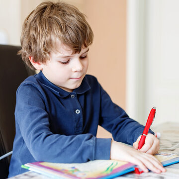 Cute little preschool kid boy at home making homework, writing letters with colorful pens. Little child doing excercise with pencils, indoors. Elementary school and education, imagine fantasy concept