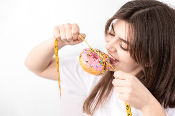 Young woman holding donut with measuring tape, isolated.