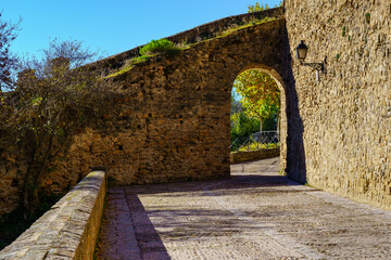 Medieval wall with arched entrance door and stone esplanade. Buitrago Lozoya Madrid.