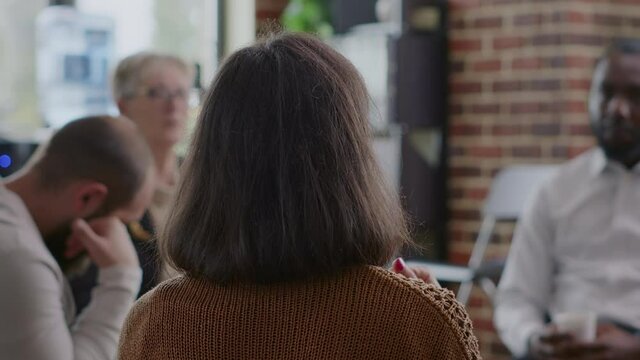 Close up of woman sharing addiction story to people in circle at aa group meeting. Person having conversation with patients and psychologist at therapy session for rehabilitation.