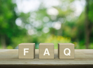 FAQ acronym on wood block cubes on wooden table over blur green tree in park, Frequently asked...