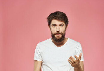 emotional man in a white t-shirt hand gestures anger pink background