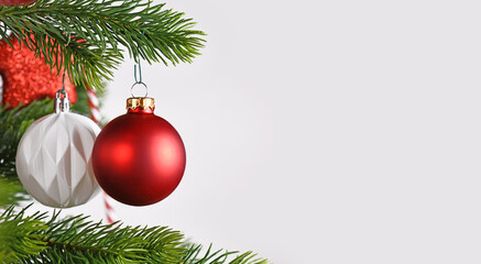 Banner with ball shaped red Christmas baubles on Christmas tree on side of gray white background with copy space