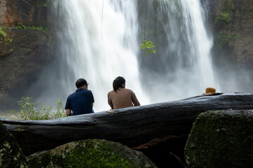 People watch the beautiful nature with trees and mountains, waterfalls. It is a tourist destination for a vacation.