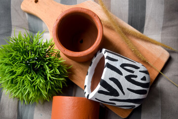 Mini terracotta  zebra pots on cutting board with hairgrass.