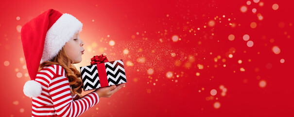 Christmas banner child in a santa hat holding a gift on a red background with place for text	
