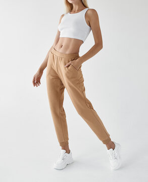 fit woman standing in light beige pants and white shirt
