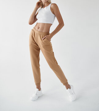 fit woman standing in light beige pants and white shirt